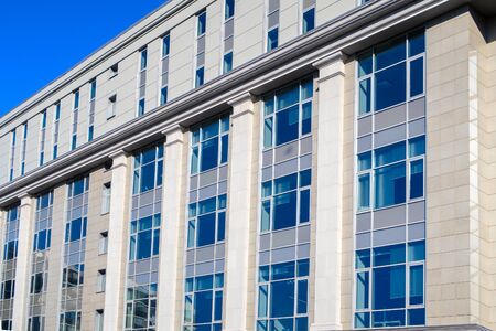 Facade of a modern office building with large glasses and clear blue sky.の写真素材