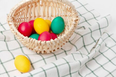 Easter colored eggs in a wicker basket on a towelの写真素材