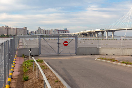 Fenced area with closed gates and a prohibition sign against the backdrop of city houses and a...