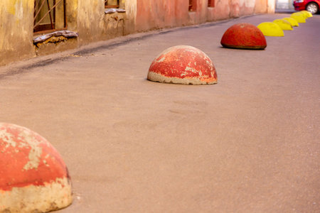 Red and yellow parking hemispheres along the wall of the building on the street. Protective barriers...