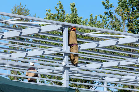 St. Petersburg, Russia - September 04, 2020: Builders are installing metal trusses at the bridge construction site. Workers have no safety equipmentのeditorial素材