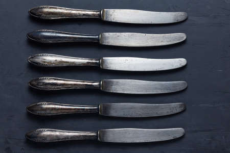 Set of old vintage cutlery knives on a dark background. Backdrop for restaurant menuの写真素材