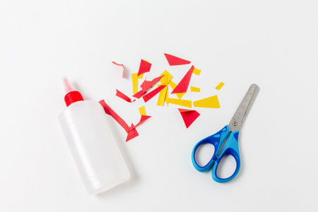 Cut multi-colored pieces of paper with scissors and glue on a light backgroundの写真素材