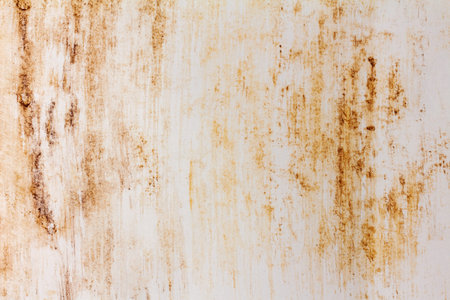 The white wall is stained with smudged streaks of rust