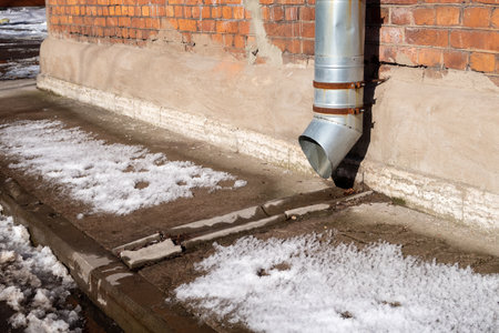 Facade of an old brick house with a downspout. A close-up on a metal rain gutter downpipeの写真素材