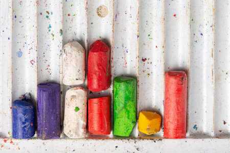Used multi-colored wax pastel crayons in a plastic box. Close-up top view. Artistic creative...