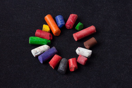 The circle or the sun is lined with colored pieces of old wax crayons on black velvet paperの写真素材