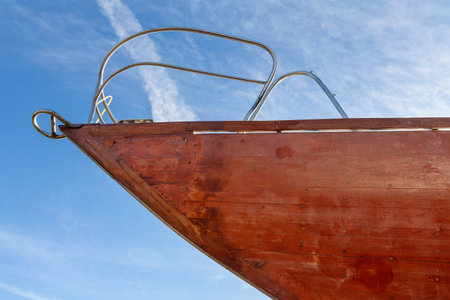 Mahogany yacht bow after varnishing against a blue sky. Repair and maintenance of watercraft. Board...