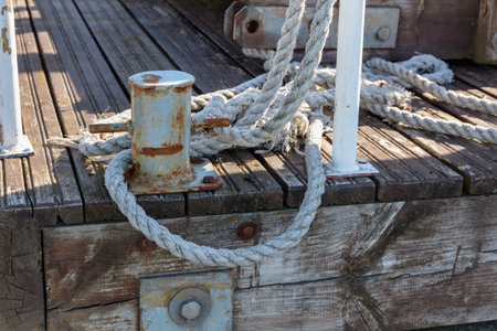 Old mooring rope knotted to a bollard on a wooden pier
