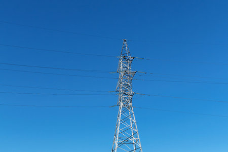 Tower and high voltage power lines on blue sky background. Electrical transmission pylon