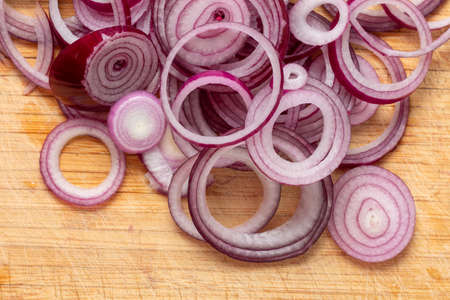 Sliced red onion rings on a wooden board top view close-upの写真素材