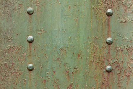 Surface of a sheet of armored metal with rivets and faded green camouflage paint. Industrial background in the style of steampunkの写真素材