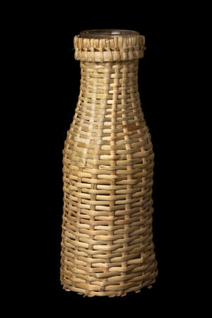 Homemade wicker wrapped glass bottle e on black backgroundの写真素材