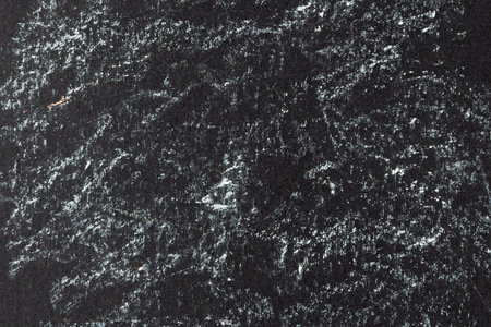 Chaotic strokes of white oil crayon on black canvas. Abstract artistic background of light paint spots on dark paperの写真素材