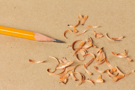 Sharpened black lead pencil and shavings on a cardboard sheet