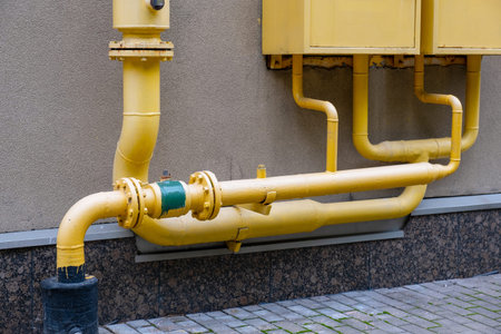 Yellow gas meter boxes with pipes and valves on the building wall. Gas equipment on the street side...