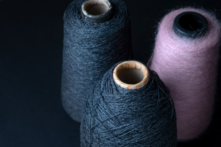 Three bobbins of merino and mohair threads for knitting on a dark background. Skeins of wool for knittingの写真素材