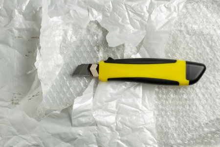 Damaged plastic envelope with cuts and a stationery knife. Postal bag with knife cuts