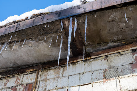 Hanging icicles on a roof. Melting snow on the roof in springの写真素材