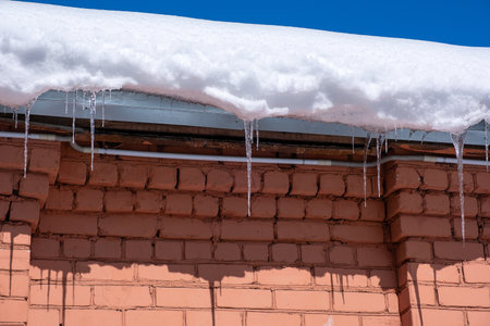 icicles hanging from the edge of the roof. Melting snow in springの写真素材