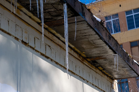 Hanging icicles on the edge of a roof with dripping waterの写真素材