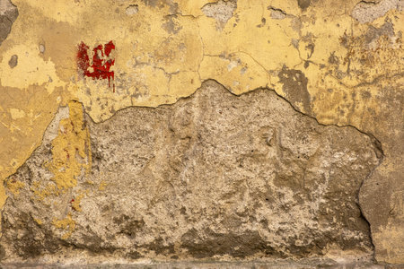 rough wall surface with old yellow plaster and red paint stainの写真素材