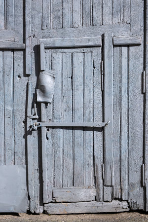 Detail of a padlocked old wooden door damaged by timeの写真素材
