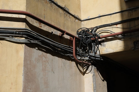 A lot of tangled wires on the wall of the building, view from the street