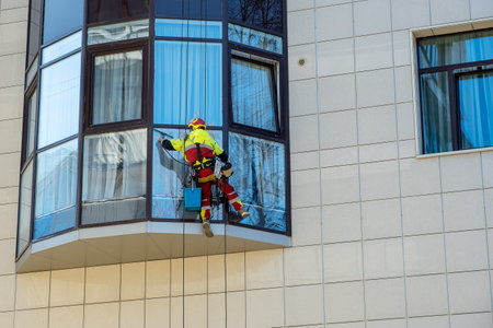 An industrial climber washes the window of a high-rise residential building. Window cleaner in...