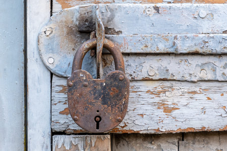 Old rusty padlock on a wooden door with peeling paintの写真素材