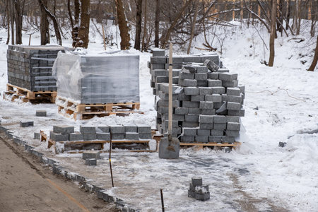 Stacks of paving slabs on a construction site covered with snow. Paving a pedestrian area in a park in winterの写真素材