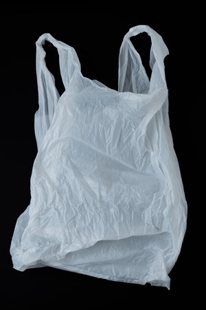 Empty crumpled white plastic bag on black background