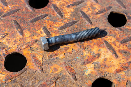 Damaged broken crooked bolt on a rusty corrugated metal sheet