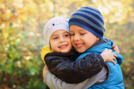 Happy embracing children, walking in the autumn parkの写真素材