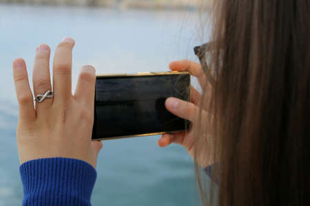 Girl photographing the seaの素材