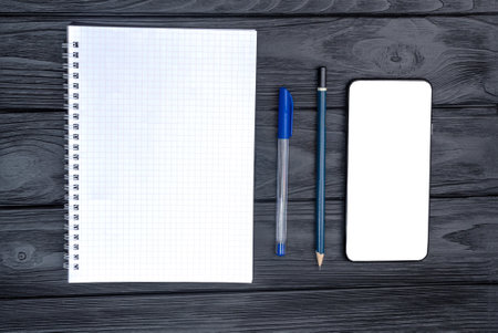 Top view of the coffee cup and notepad with pen and empty smartphone on the wooden table.の写真素材