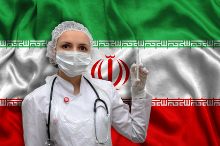 Young woman doctor in medical uniform on the background of the national flag of Iran is holding a syringe. The concept of a new vaccine against the disease, flu vaccine vaccinationの写真素材