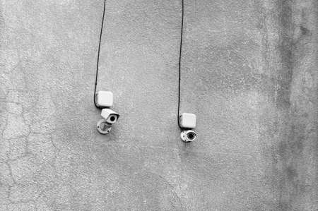 Two modern cctv cameras on the dirty wall of a building on the streetの写真素材