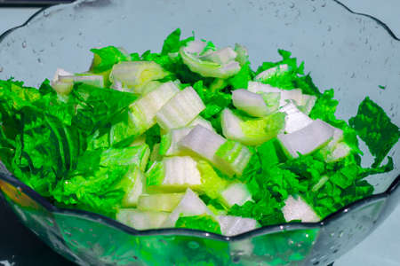 Fresh chopped napa cabbage in a glass salad bowl. Making a healthy summer salad with fresh green vegetables. Chinese cabbage salad. Grainy effectの写真素材