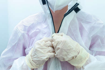 The process of putting on a medical protective anti-plague suit close-up. A young female medical practitioner in a protective medical suit to combat Covid-19の写真素材