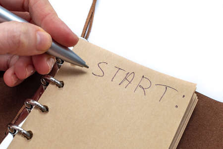 A woman's hand wrote with a pen in a notebook: Start. the concept of starting a new, achieving goals.の写真素材