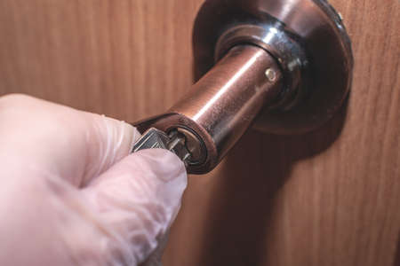 The hand of a man in a latex glove opens the door with a key. Intrusion concept.の写真素材