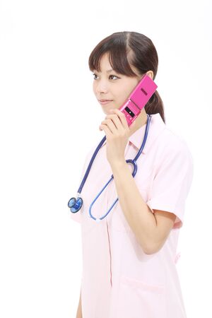 Young asian female nurse calling by cellular phoneの写真素材