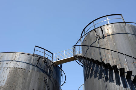 old black storage tank with stairs against a blue skyの写真素材
