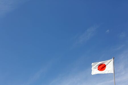Japanese flag in wind against clear blue skyの写真素材