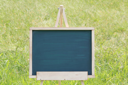 blank chalkboard with wooden easel on green fieldの写真素材