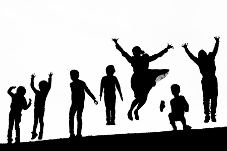 Shadow people playing and jumping on top of the hillの写真素材