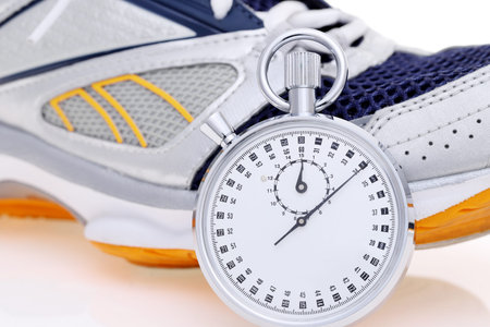 analogue stopwatch with sport running shoes on white background