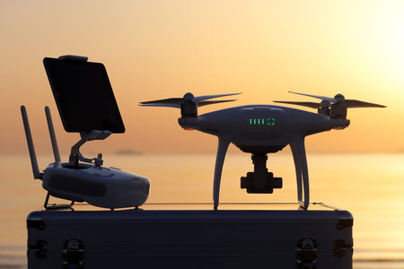 Drone with remote controller before the flight, tool for aerial photo and video against sunset sky