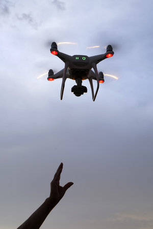 Hand catching drone aircraft in sunset sky background